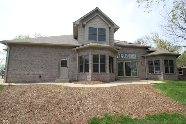 back of property featuring a patio, a shingled roof, and brick siding