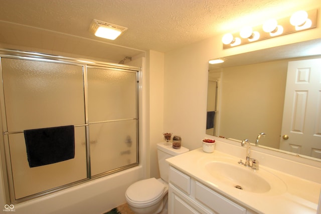 bathroom with toilet, vanity, a textured ceiling, and bath / shower combo with glass door