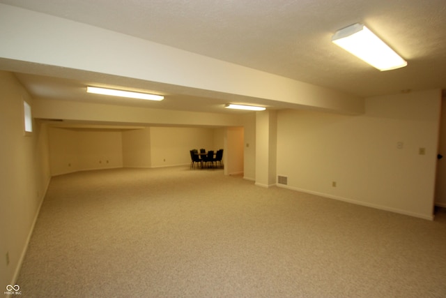 finished basement featuring light colored carpet, baseboards, and visible vents