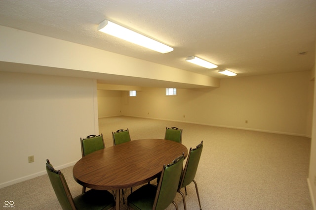 carpeted dining area featuring a textured ceiling and baseboards