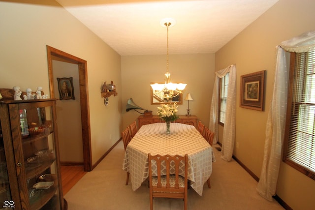 dining space with an inviting chandelier, light carpet, and baseboards