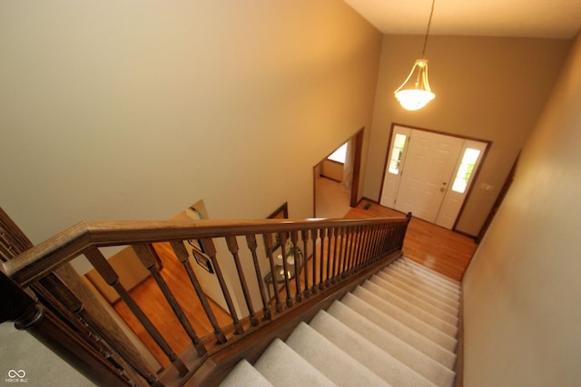 stairway with a towering ceiling and wood finished floors