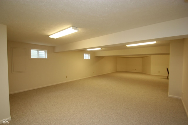 below grade area featuring light colored carpet, a wealth of natural light, and baseboards