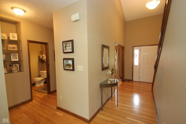 hall featuring light wood-style flooring and baseboards