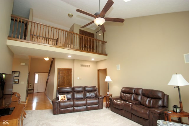 living area with ceiling fan, carpet flooring, a high ceiling, and visible vents
