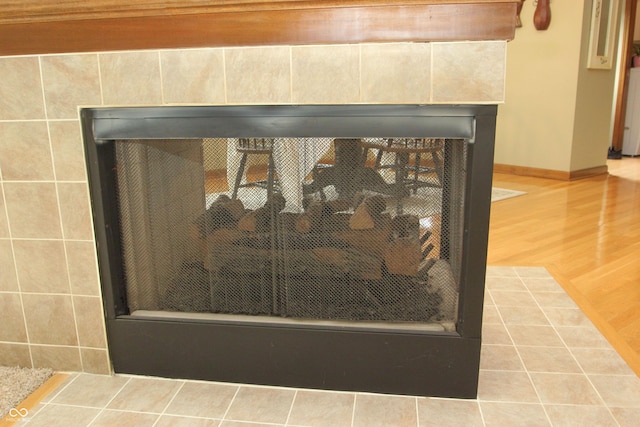 details featuring baseboards, a tile fireplace, and wood finished floors