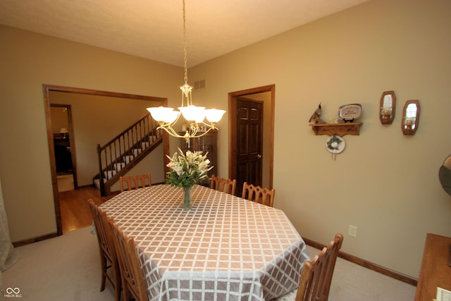 dining space featuring carpet, visible vents, baseboards, a chandelier, and stairs