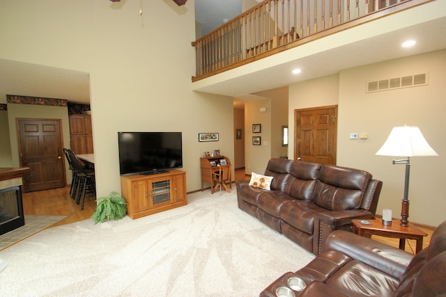 living area with a ceiling fan, recessed lighting, visible vents, a towering ceiling, and a tile fireplace