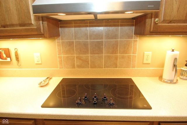 details featuring brown cabinetry, range hood, decorative backsplash, black electric cooktop, and light countertops