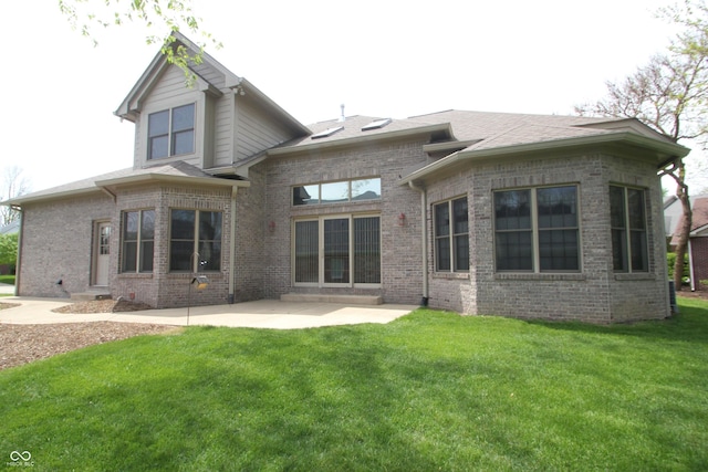 back of house featuring a lawn, a patio, brick siding, and a shingled roof
