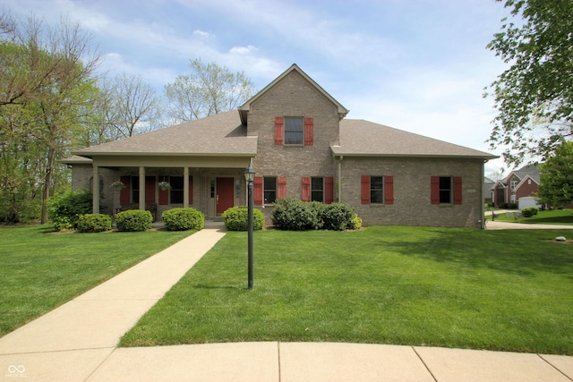 view of front of property with covered porch, a shingled roof, a front lawn, and brick siding
