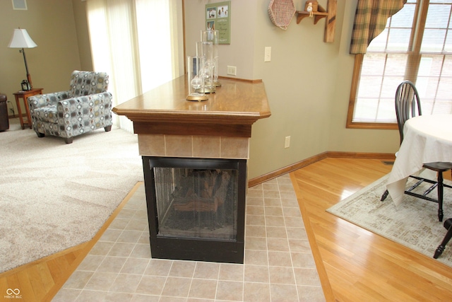 living room with a tile fireplace, wood finished floors, and baseboards