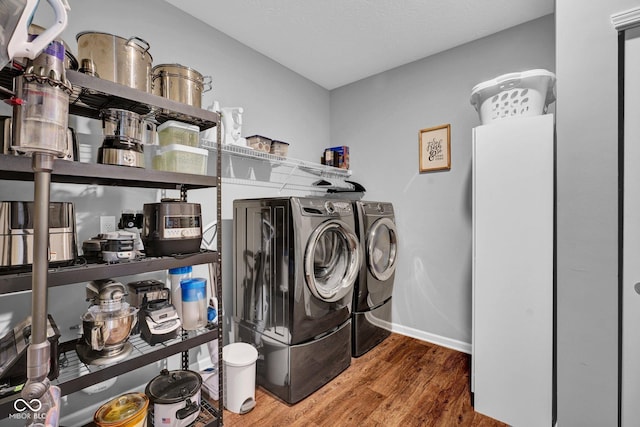 clothes washing area with baseboards, separate washer and dryer, laundry area, and wood finished floors