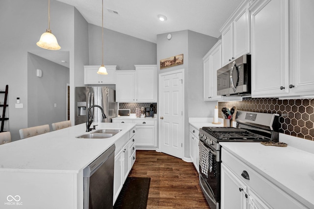 kitchen with a sink, stainless steel appliances, pendant lighting, light countertops, and decorative backsplash