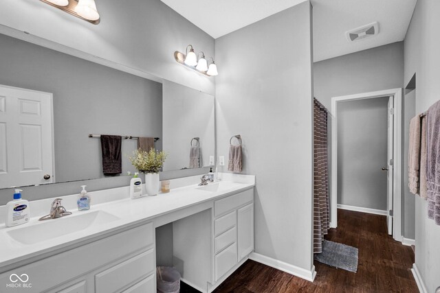 full bathroom featuring double vanity, visible vents, wood finished floors, and a sink