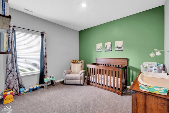 bedroom with a crib, carpet, visible vents, and baseboards