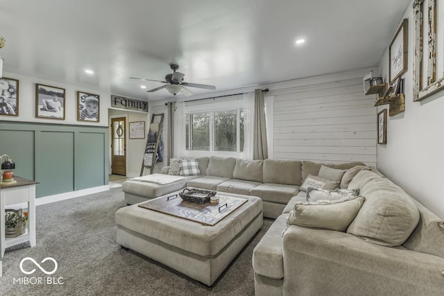 carpeted living area featuring a ceiling fan, a decorative wall, and recessed lighting