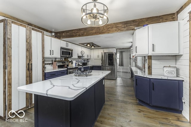 kitchen with blue cabinets, stainless steel appliances, white cabinetry, and a center island
