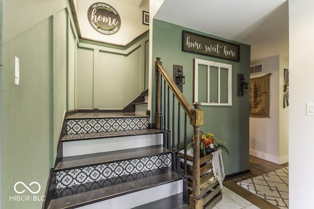 staircase featuring tile patterned floors, visible vents, and baseboards