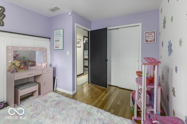 bedroom featuring a closet, visible vents, wood finished floors, and baseboards