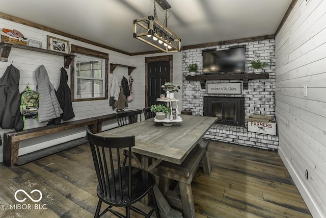 dining area with ornamental molding, a brick fireplace, wooden walls, and wood-type flooring
