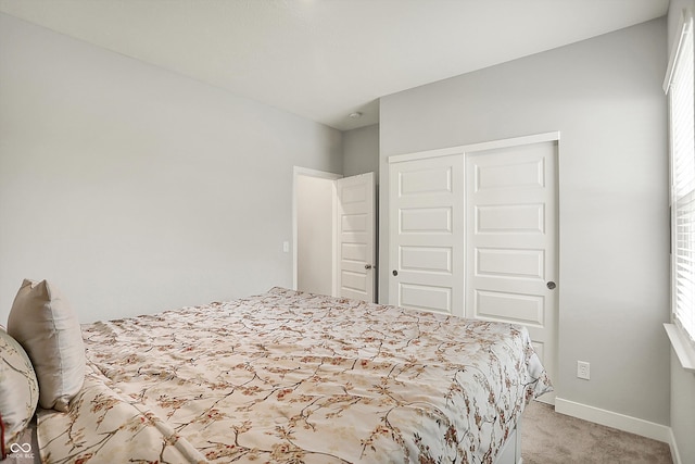 bedroom with light carpet, a closet, and baseboards