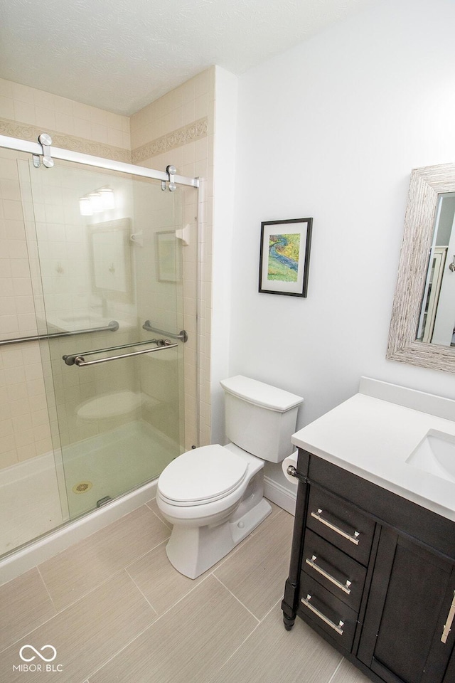 bathroom featuring toilet, a shower stall, and vanity