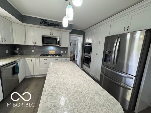 kitchen with appliances with stainless steel finishes, white cabinetry, crown molding, decorative backsplash, and decorative light fixtures