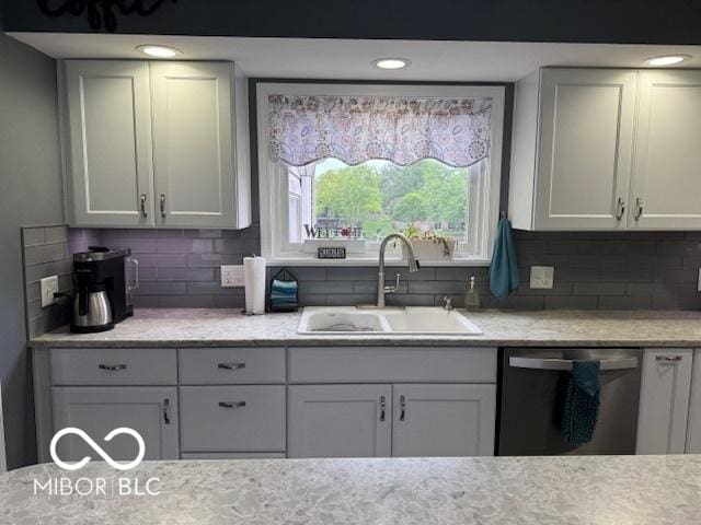 kitchen with stainless steel dishwasher, a sink, tasteful backsplash, light stone counters, and white cabinetry