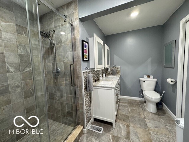 bathroom featuring toilet, a shower stall, and vanity