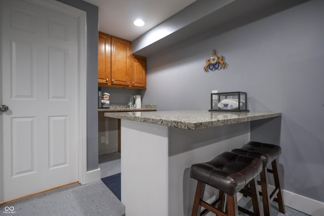 3829 Waycross Dr, Columbus, IN 47203 - kitchen featuring baseboards, a peninsula, a breakfast bar area, brown cabinets, and recessed lighting