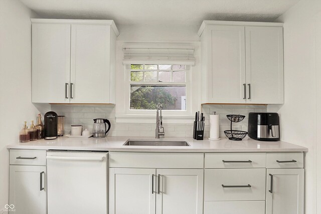 kitchen with dishwasher, a sink, backsplash, and white cabinets