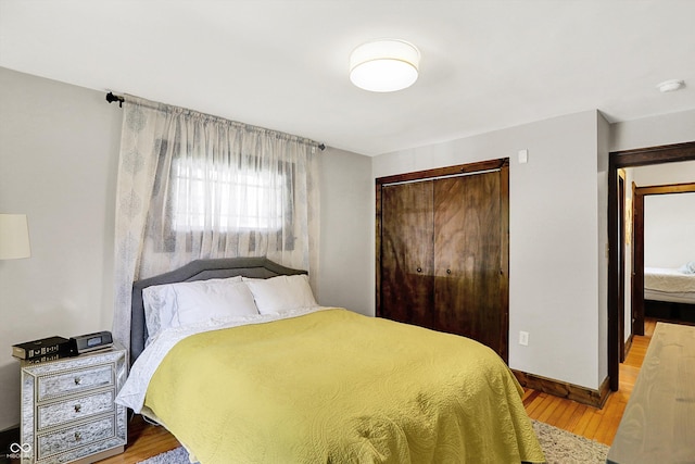 bedroom with a closet, light wood-style flooring, and baseboards