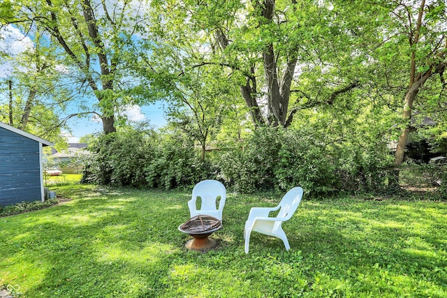 view of green lawn with an outdoor fire pit