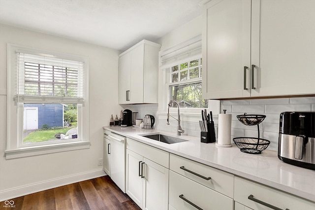 kitchen with a sink, baseboards, white dishwasher, tasteful backsplash, and light countertops
