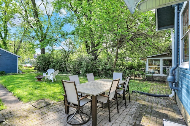 view of patio featuring an outdoor fire pit, outdoor dining space, and a sunroom