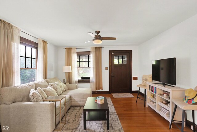 living room with healthy amount of natural light, wood finished floors, a ceiling fan, and baseboards