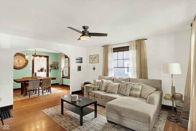 living room with arched walkways, ceiling fan, wood finished floors, and baseboards