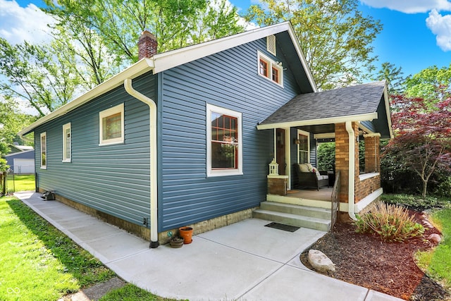 view of front of home with a chimney, a shingled roof, and a porch