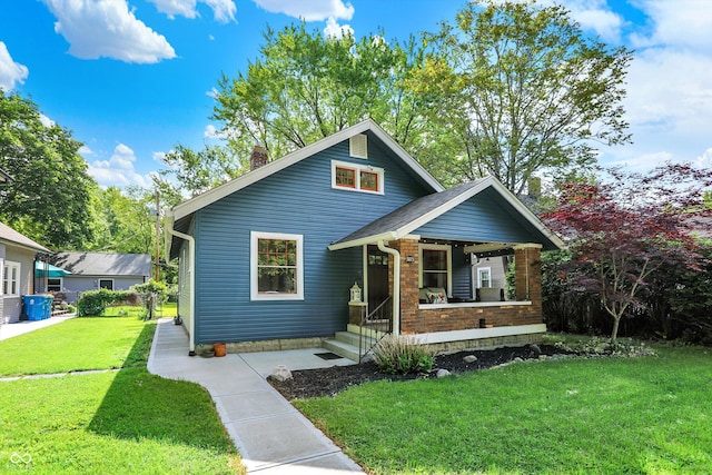 view of front of home featuring covered porch, a front yard, and a chimney