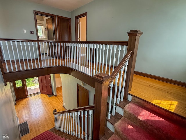 stairway with wood finished floors, healthy amount of natural light, baseboards, and arched walkways