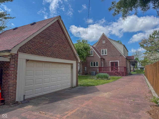 view of home's exterior with brick siding, cooling unit, a garage, and a deck