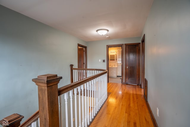 hall featuring an upstairs landing, light wood-style floors, and baseboards