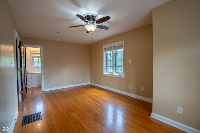 empty room with plenty of natural light, a ceiling fan, light wood-style floors, and baseboards