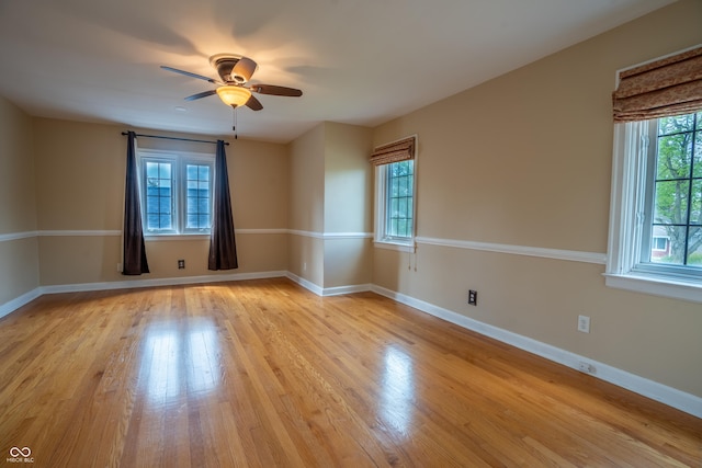 spare room featuring a ceiling fan, light wood-style flooring, and baseboards