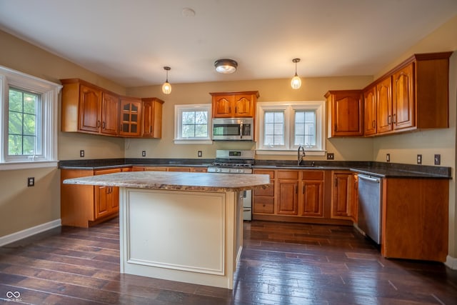 kitchen with stainless steel appliances, brown cabinetry, a sink, and dark wood-type flooring