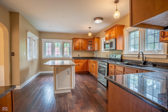 kitchen with stainless steel appliances, a sink, brown cabinets, and plenty of natural light