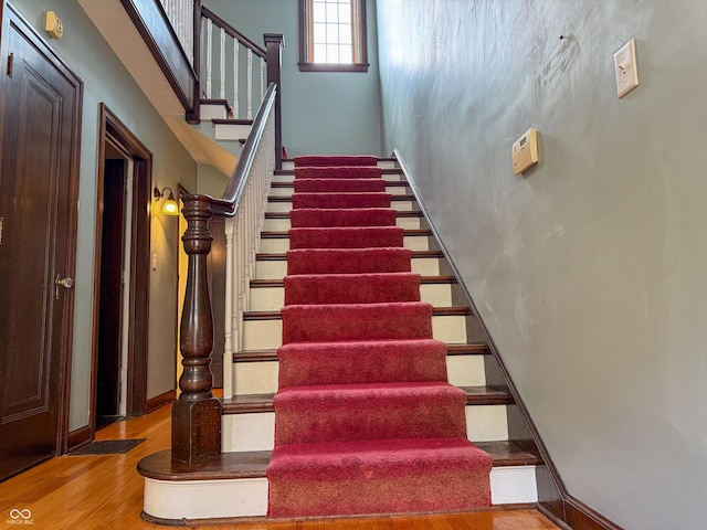 stairs featuring wood finished floors and a high ceiling