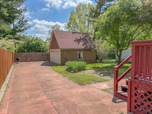view of side of property featuring brick siding, an outbuilding, fence, and roof with shingles