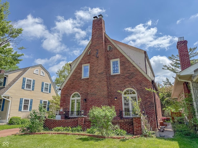 rear view of house featuring brick siding and a chimney